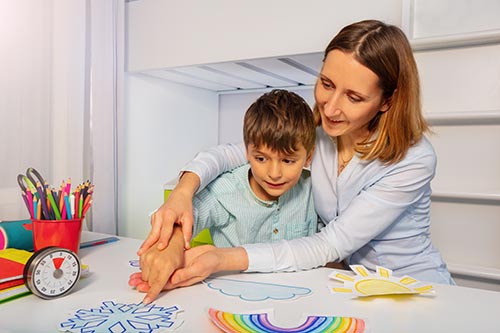 Woman guides child to look at drawings as they discuss weather