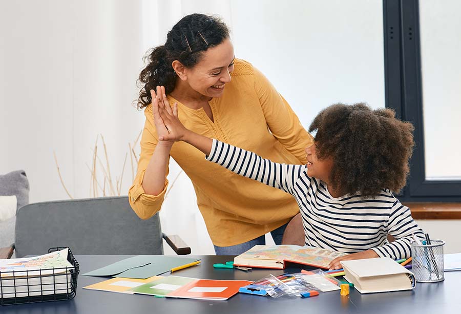 Child high fives woman as they do arts and crafts