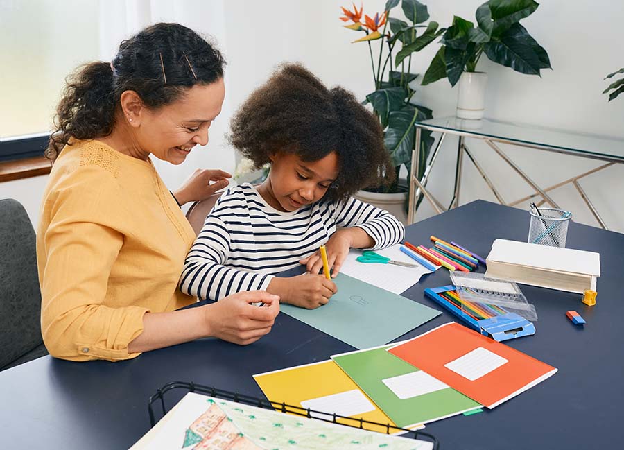 Woman helps girl draw a picture