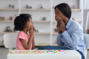 Woman shows child an excercise during ABA therapy for challenging behaviors