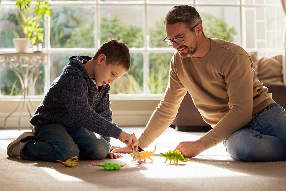 Man and son sit on floor and try autism communication strategies