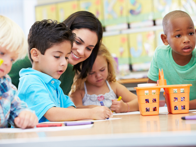 Therapist works with children at table drawing
