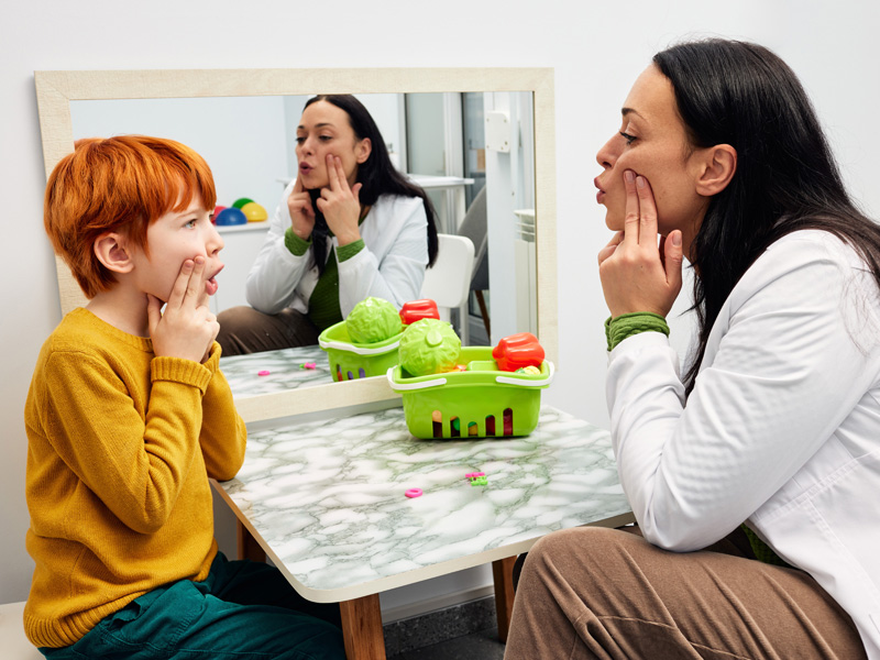Therapist teaching boy with speech therapy