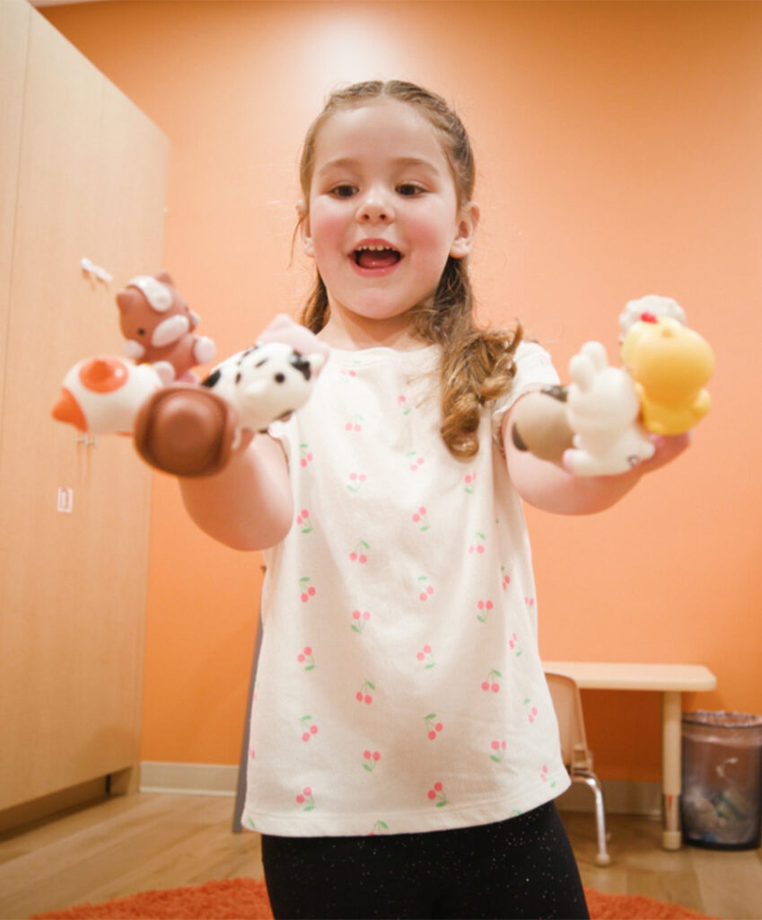 Child showing off both hands with a finger puppet on each finger.