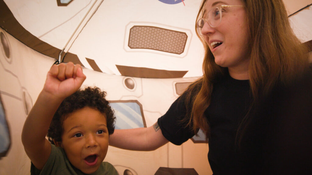Child and adult playing astronaut in a fake spaceship fort.