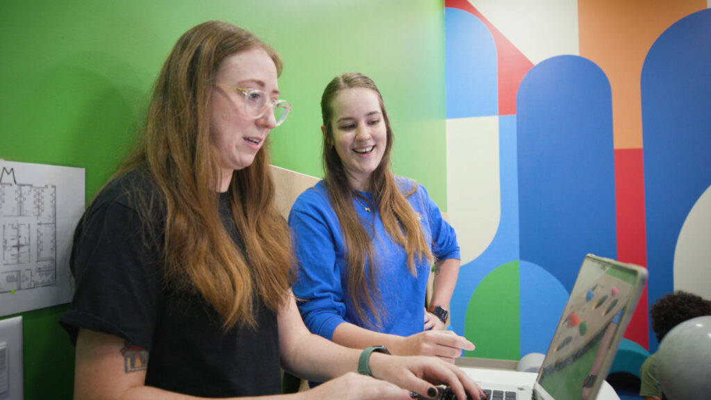 Two adults looking at computer video feed.