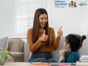 ABA therapist encouraging a child with thumbs up during therapy session
