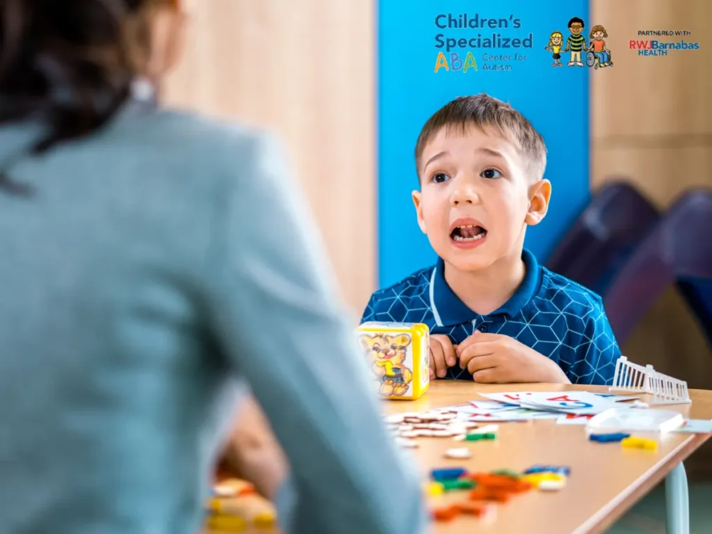 Parent learning ABA strategies from therapist during coaching session with child