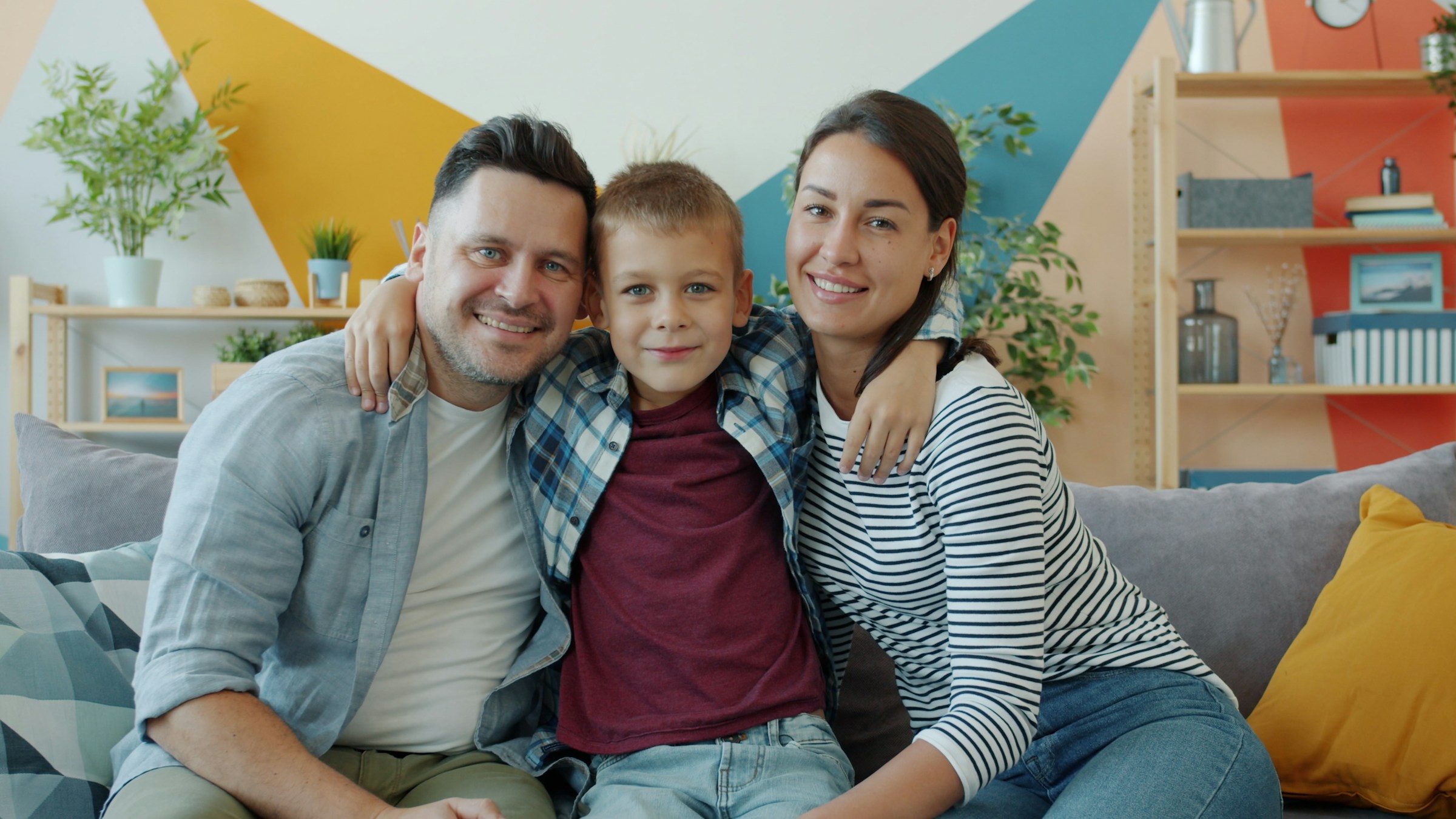 A happy family of three sharing a supportive moment together at home, showcasing the positive impact of family-centered care and parent coaching.