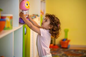 Young girl reaching for toy demonstrating chore independence and fostering autonomy in autism therapy.