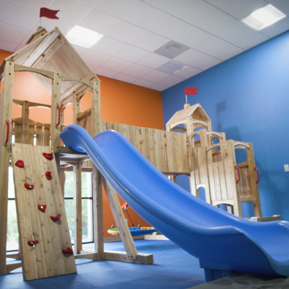 Indoor wooden playground with a slide.