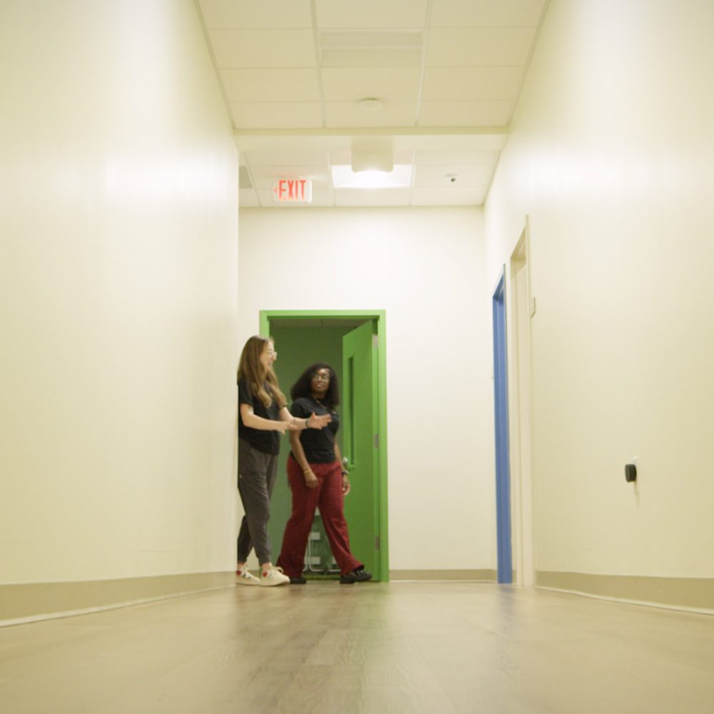 Two teachers walking down hallway talking.