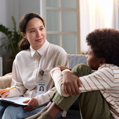 Portrait of female psychologist talking to young child in therap